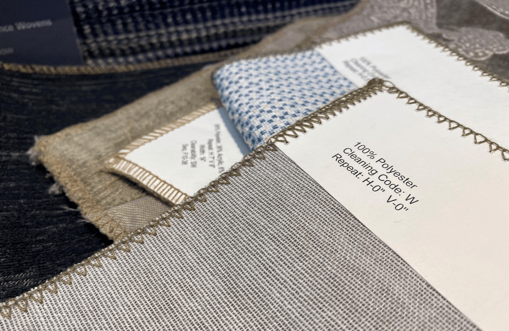 Close-up of various fabric samples, showcasing different textures and patterns. A fabric label indicating 